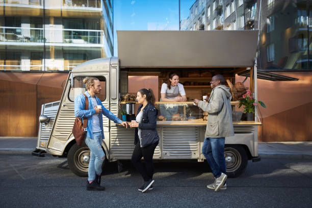 female owner in concession stand while customers having food and drink on street in city - junk food stock pictures, royalty-free photos & images