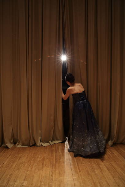 female peeking through curtains of concert hall stage,rear view - concert stock pictures, royalty-free photos & images