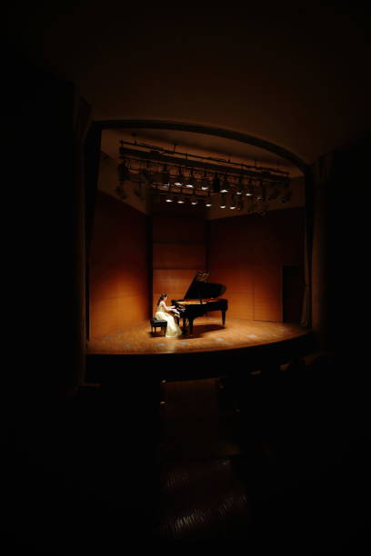 female pianist playing grand piano at concert hall - concert stock pictures, royalty-free photos & images