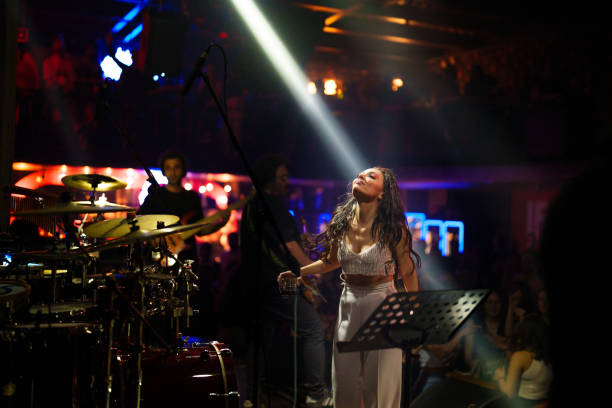 female singer on stage with spotlight - concert stock pictures, royalty-free photos & images