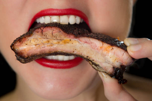 female with lipstick eating bbq ribs - junk food stock pictures, royalty-free photos & images