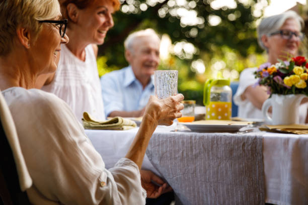 femme profitant d’une boisson rafraîchissante et traînant avec des amis lors d’un dîner d’été relaxant - garden decoration photos et images de collection