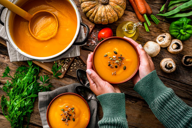 femme tenant un bol de soupe à la citrouille pour le repas de thanksgiving - food photos et images de collection