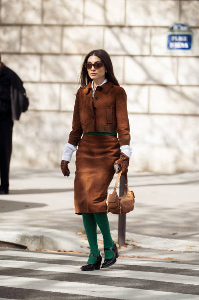 Fer Millan wears green tights, brown skirt, white shirt, brown jacket and brown bag outside the Miu Miu show during Womenswear Spring/Summer 2025 as...