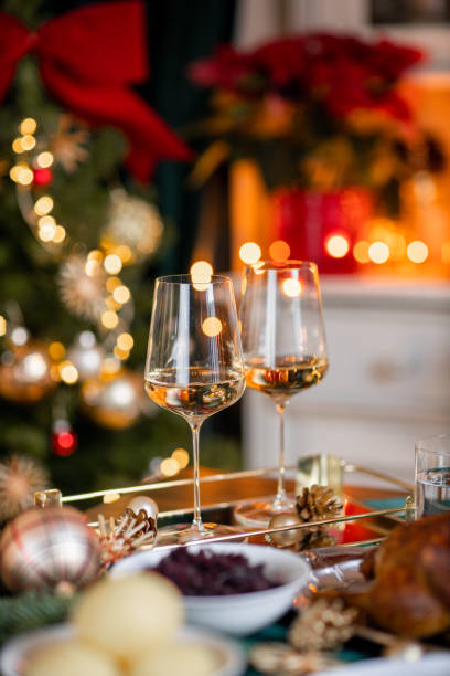 festive christmas dinner table with white wine glasses with roast goose turkey in cozy home - home decoration stock pictures, royalty-free photos & images