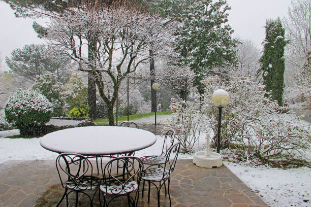 first snow, patio with table and chairs, meadow and trees - garden decoration photos et images de collection