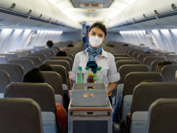 flight attendant serving drinks in an airplane wearing a facemask - food stock pictures, royalty-free photos & images