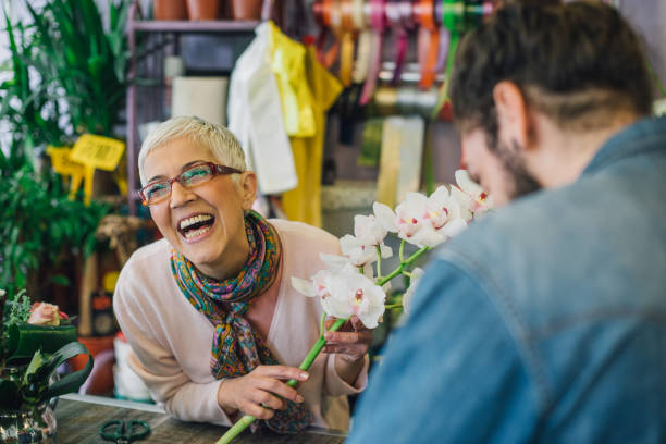 florist laughing with a customer in a flower shop - garden decoration stock pictures, royalty-free photos & images