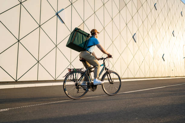 food delivery person riding bicycle, delivering food - food stock pictures, royalty-free photos & images