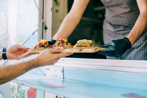 food truck owner serving tacos to male customer. - junk food stock pictures, royalty-free photos & images