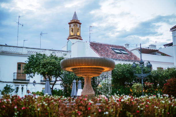 fountain with flowers in the town square of estepona, malaga, spain at sunset - garden decoration stock pictures, royalty-free photos & images