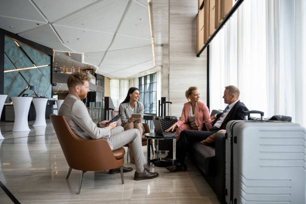 four colleagues sitting in a luxury hotel lobby and preparing for a business meeting. - travel stock pictures, royalty-free photos & images