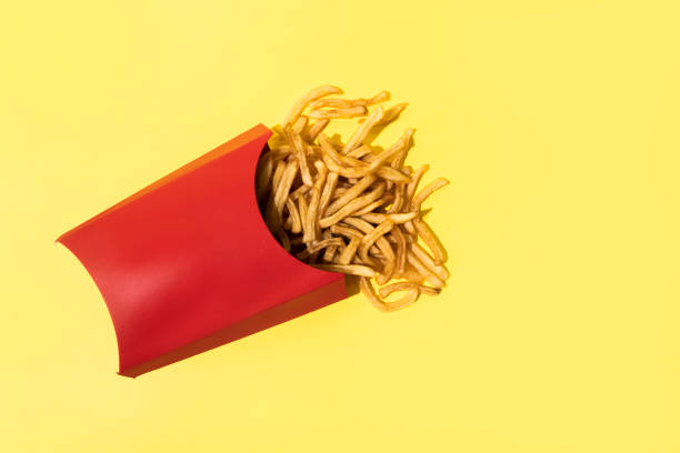 french fries on yellow background - junk food stock pictures, royalty-free photos & images