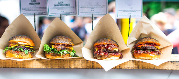 fresh flame grilled burgers displayed in a row at food market - junk food stock pictures, royalty-free photos & images
