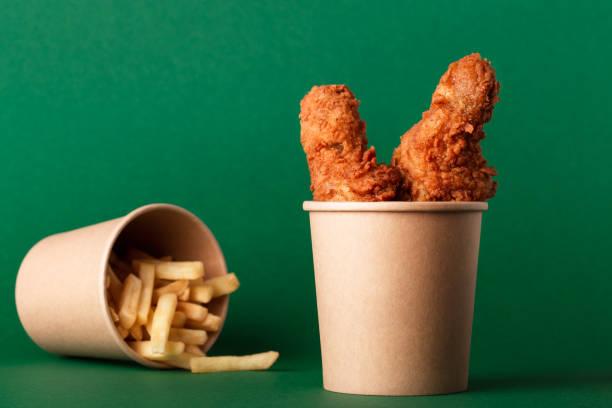 fried crispy chicken legs, drumsticks in craft paper cup on green - junk food stock pictures, royalty-free photos & images