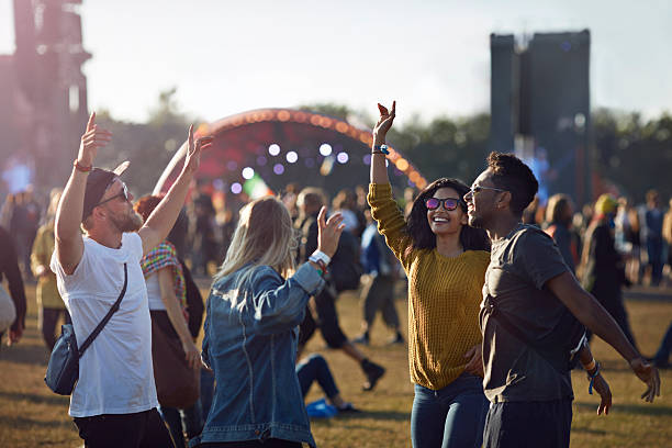 friends dancing at festival with arms in air - concert stock pictures, royalty-free photos & images