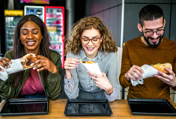 friends eating in fast food restaurant - junk food stock pictures, royalty-free photos & images