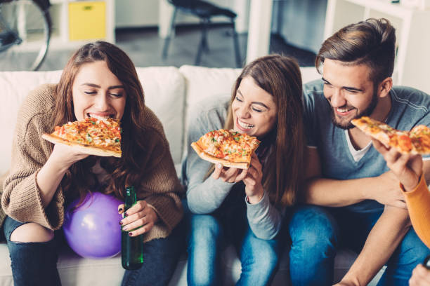 friends eating pizza at home - junk food stock pictures, royalty-free photos & images