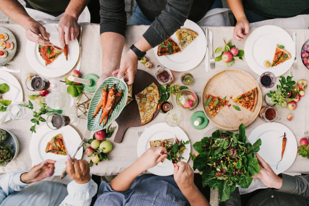 friends enjoying a dinner together in greenhouse harvest party - food stock pictures, royalty-free photos & images