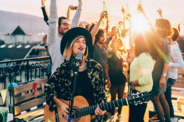 friends enjoying a guitar performance on the rooftop - concert stock pictures, royalty-free photos & images
