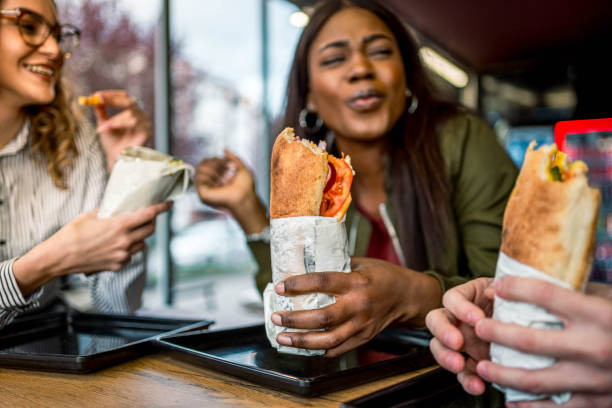 friends having lunch together in a fast-food restaurant - junk food stock pictures, royalty-free photos & images