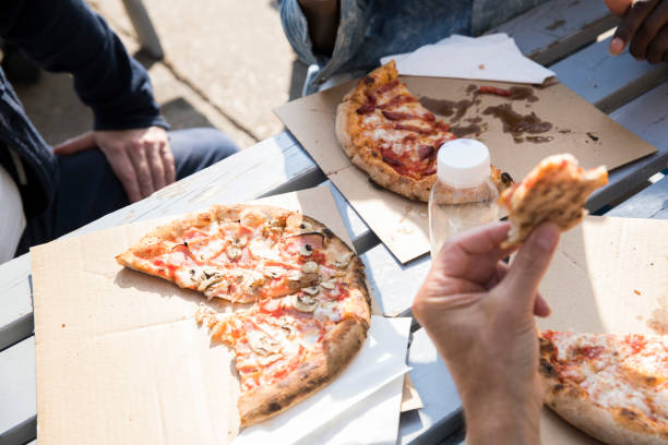 friends having pizza outdoors - junk food stock pictures, royalty-free photos & images