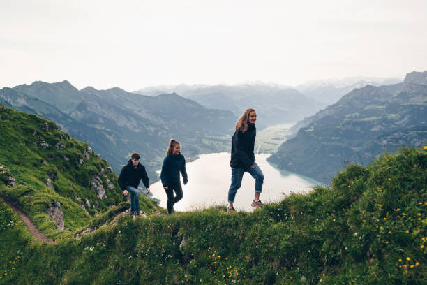 friends hike up grassy mountain ridge at sunrise - travel stock pictures, royalty-free photos & images