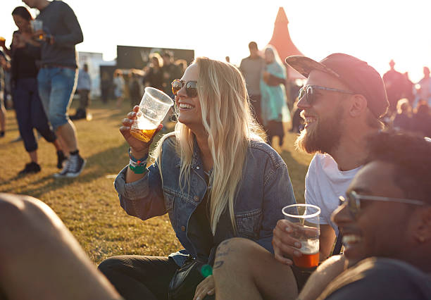 friends laughing at big festival, holding beers - concert stock pictures, royalty-free photos & images