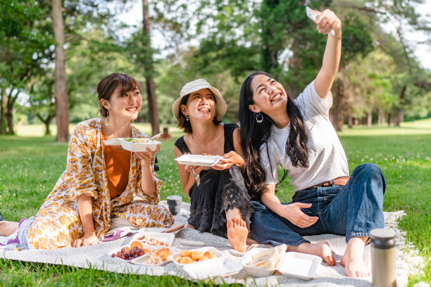 friends taking selfies while enjoying having picnic in nature - junk food stock pictures, royalty-free photos & images