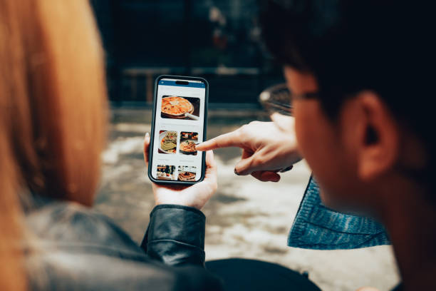 friends using mobile food delivery app to browse menu and order online - junk food stock pictures, royalty-free photos & images
