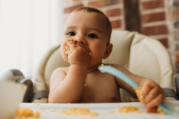 funny baby eating healthy food on kitchen - food stock pictures, royalty-free photos & images
