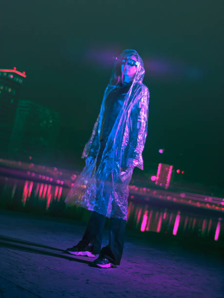 futuristic woman standing on a street in neon city at rainy night - fashion stock pictures, royalty-free photos & images
