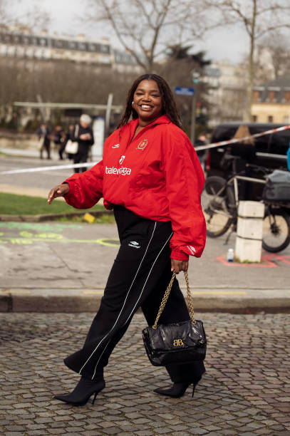 Gabriella Karefa-Johnson wears black pants, red sport jacket from Balenciaga and black bag outside Balenciaga during the Womenswear Fall/Winter...