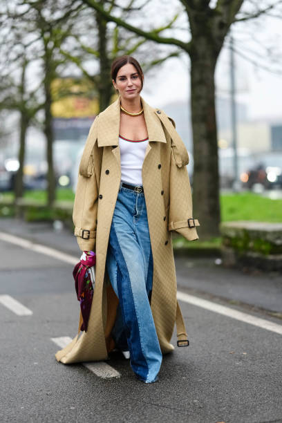 Gala Gonzalez wears gold necklace, light yellow Gucci monogram oversized Gucci trench coat, white Gucci tank top, black Gucci leather belt, light...
