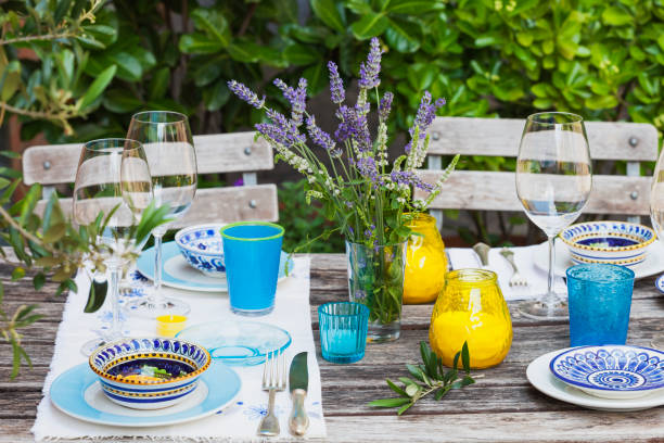 garden table laid with colorful plates and bowls - garden decoration stock pictures, royalty-free photos & images