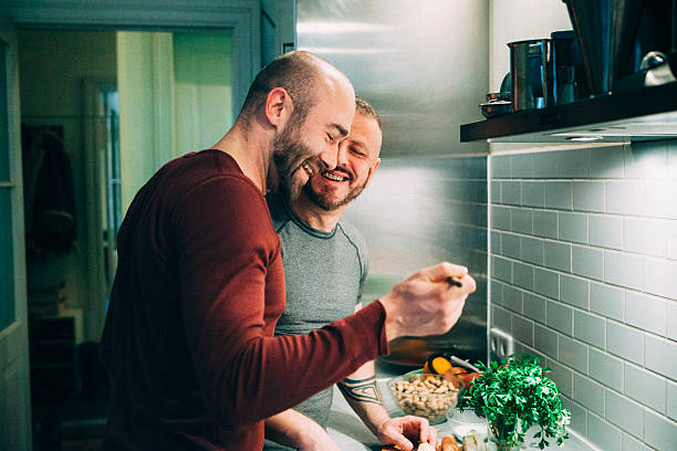 gay couple preparing the meal in the kitchen - food stock pictures, royalty-free photos & images
