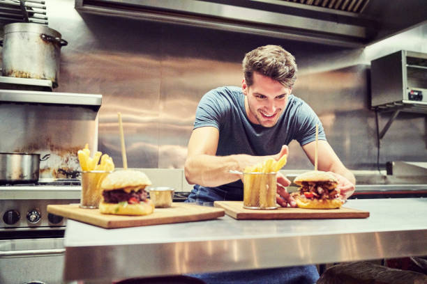 gelukkig chef-kok schikken hamburger en frietjes - junk food stockfoto's en -beelden