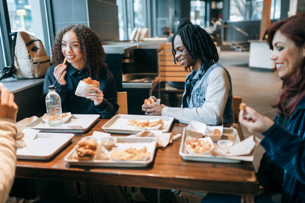 gen z friends eating food at local venue - junk food stock pictures, royalty-free photos & images