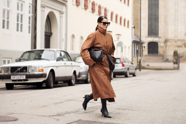 Gili Biegun wears, long brown leather coat, black bag, black long leather gloves, sunglasses and black shoes during the Copenhagen Fashion Week...