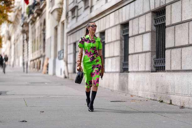Ginevra Mavilla wears black sunglasses, gold earrings, bright green hot pink black floral pattern/detail short sleeve Miu Miu midi dress, shiny dark...