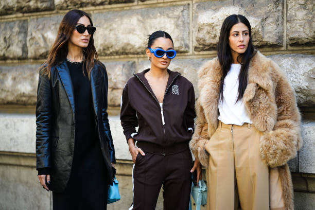 Giorgia Tordini wears black sunglasses from Loewe, a silver large chain necklace, a black midi long dress, a black shiny leather blazer jacket, a...