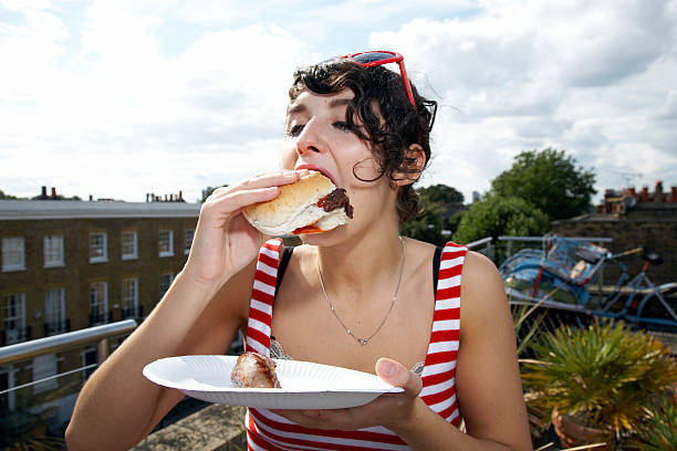 girl eating a huge burger - junk food stockfoto's en -beelden
