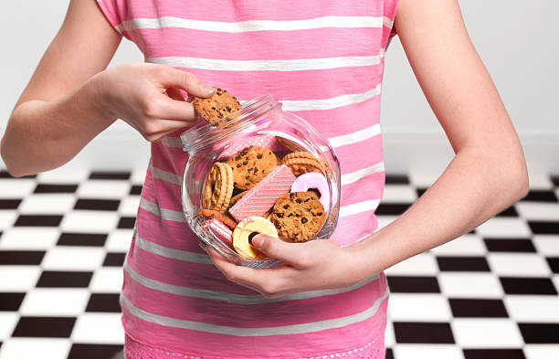 girl eating cookies - junk food stock pictures, royalty-free photos & images