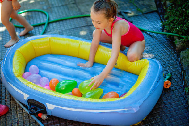 girl playing water balloons fight in summer - garden decoration stock pictures, royalty-free photos & images