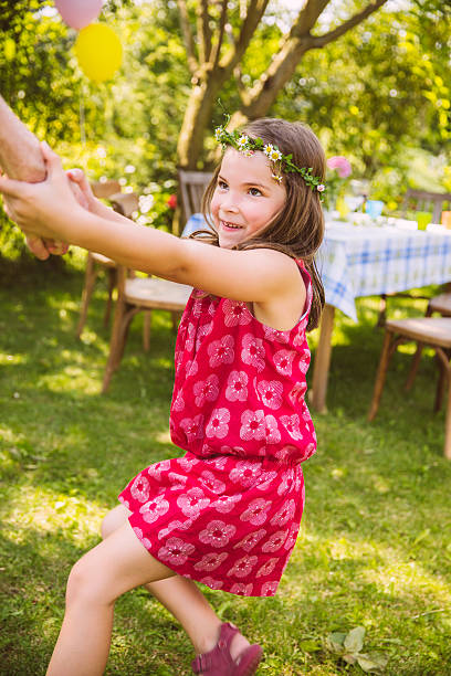 girl pulling adult's arm in garden - garden decoration stock pictures, royalty-free photos & images