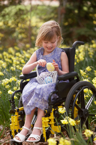 girl sitting on a wheelchair and holding a basket of easter eggs - garden decoration stock pictures, royalty-free photos & images