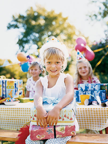girl sitting on bench holding wrapped birthday presents - garden decoration stockfoto's en -beelden
