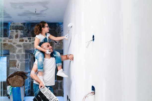 girl sitting on father's shoulders painting the wall of her new house - home decoration stock pictures, royalty-free photos & images