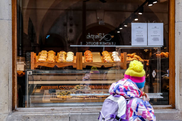 Girl walks past a shop with fresh doughnuts on Fat Thursday , February 8, 2024 in central Krakow, Poland. Fat Thursday is a Polish tradition, with...