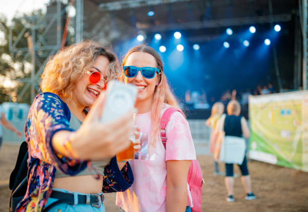 girlfriends taking selfie on daytime outdoor music festival - concert stock pictures, royalty-free photos & images